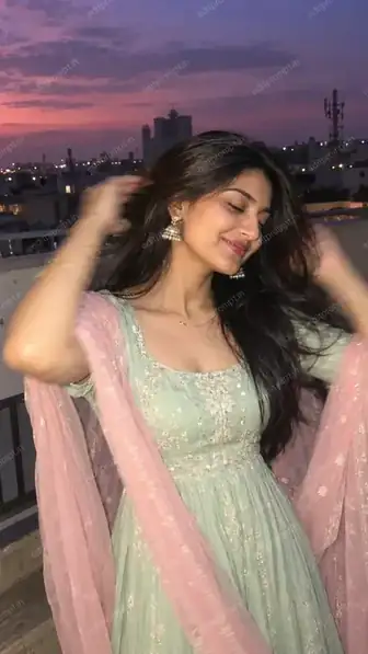 Traditional motion blur AI photo prompt - girl in a mint anarkali and pink dupatta sweeping her hair back on a rooftop at blue hour, lit by flash